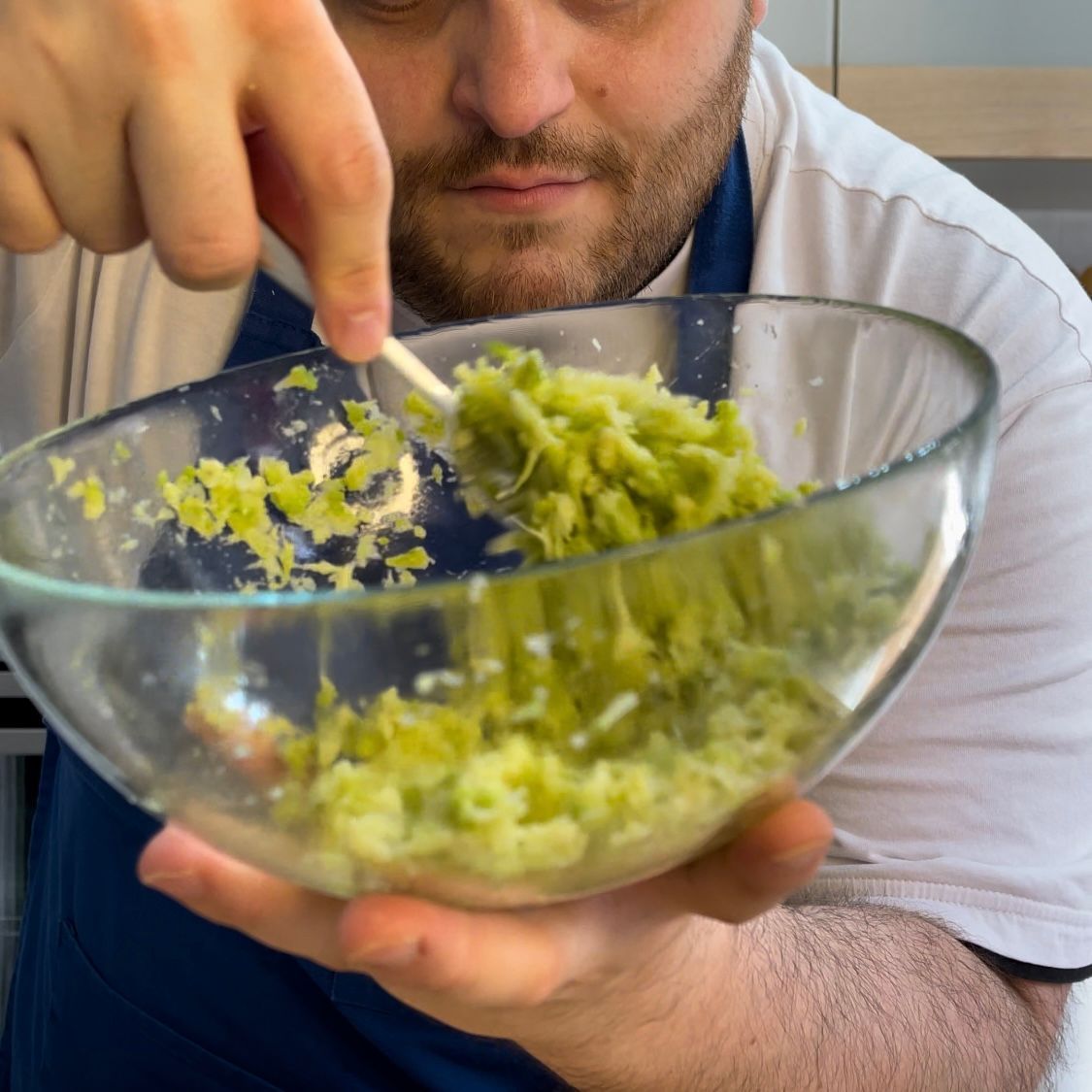 Un uomo sta mescolando una ciotola di verdure verdi con un cucchiaio