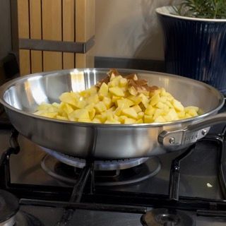 Cubetti di mela che cuociono in padella con burro, zucchero e cannella.