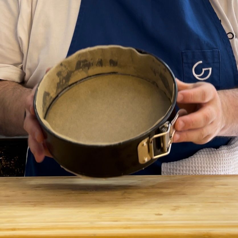 Un uomo con un grembiule tiene in mano una tortiera