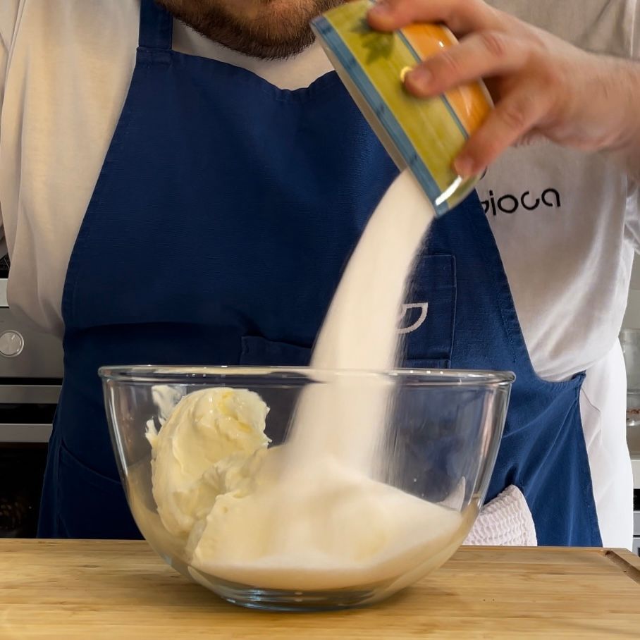 Un uomo sta versando lo zucchero in una ciotola di vetro