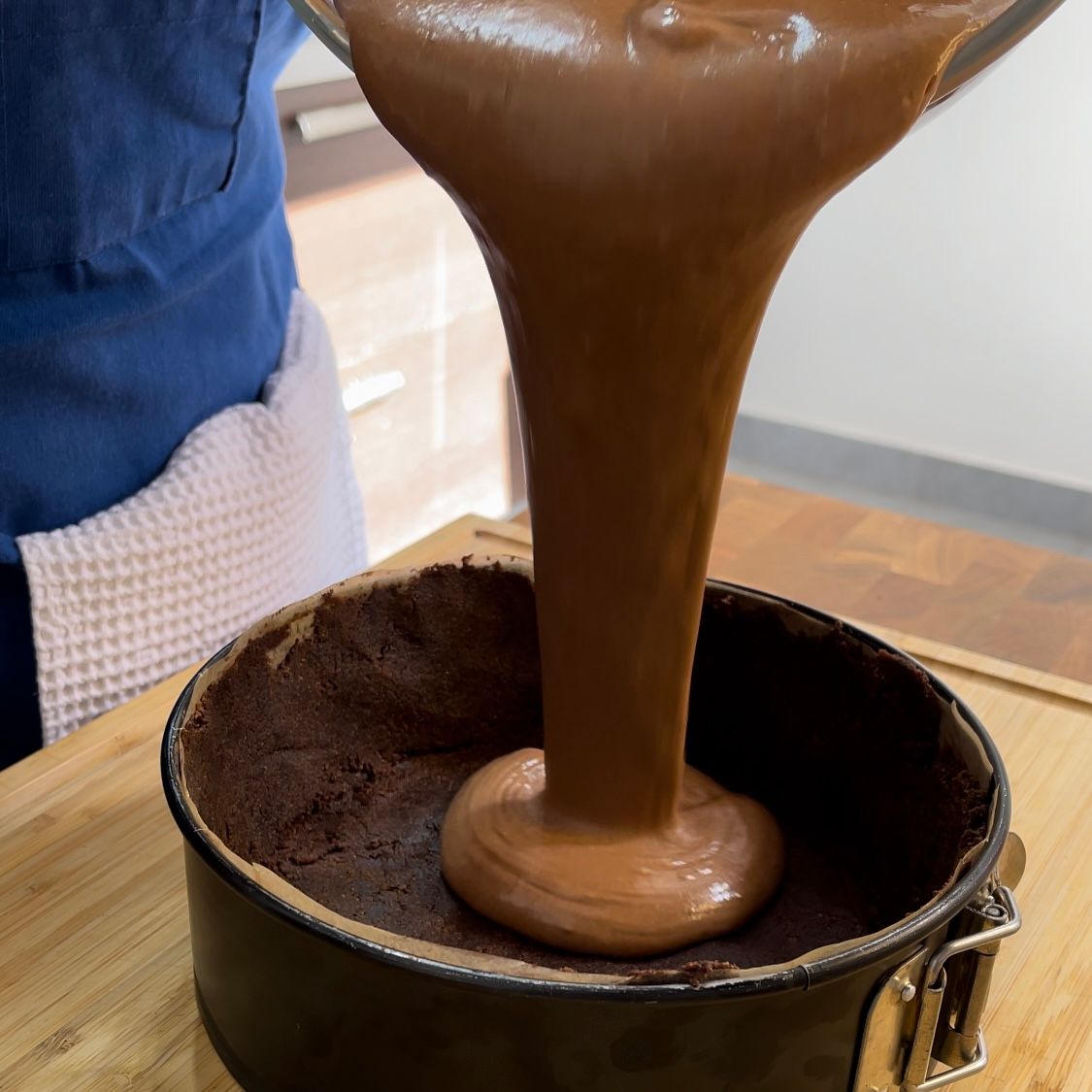 Una persona sta versando il cioccolato in una tortiera