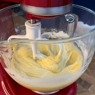 Un mixer rosso sta mescolando un liquido giallo in una ciotola di vetro