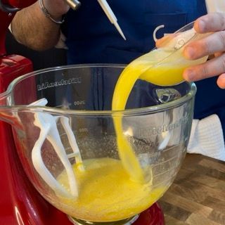 Una persona che versa del liquido giallo in un misurino di vetro