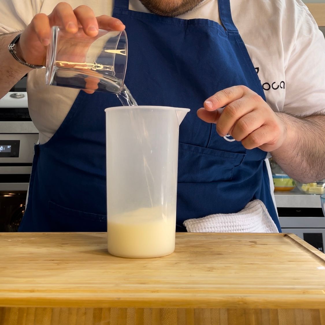 Un uomo con un grembiule sta versando del liquido in un misurino.