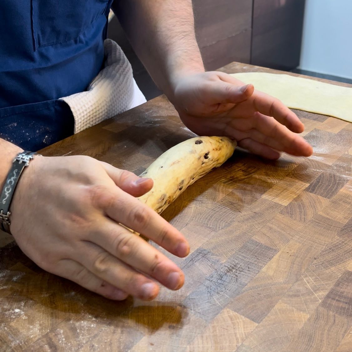 Una persona tiene in mano una banana su un tagliere di legno.