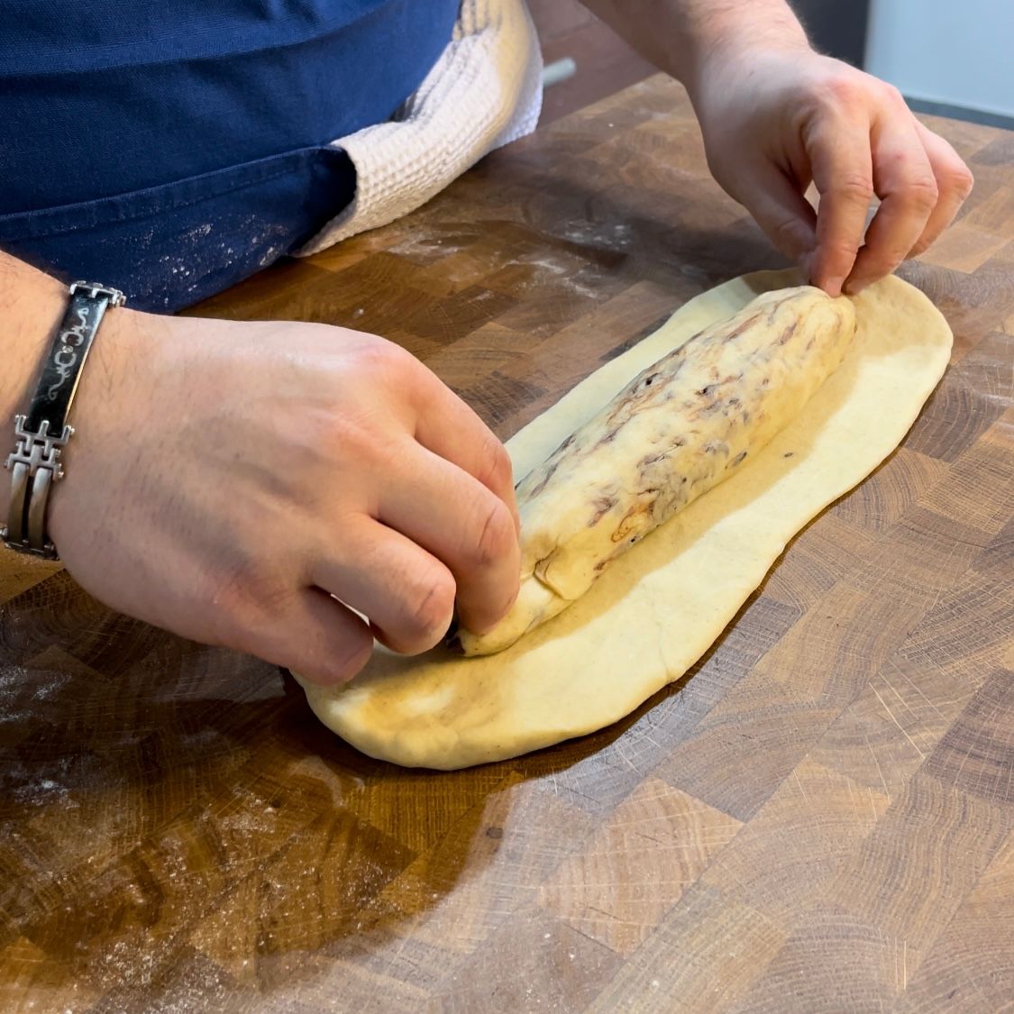Una persona sta stendendo la pasta su un tagliere di legno