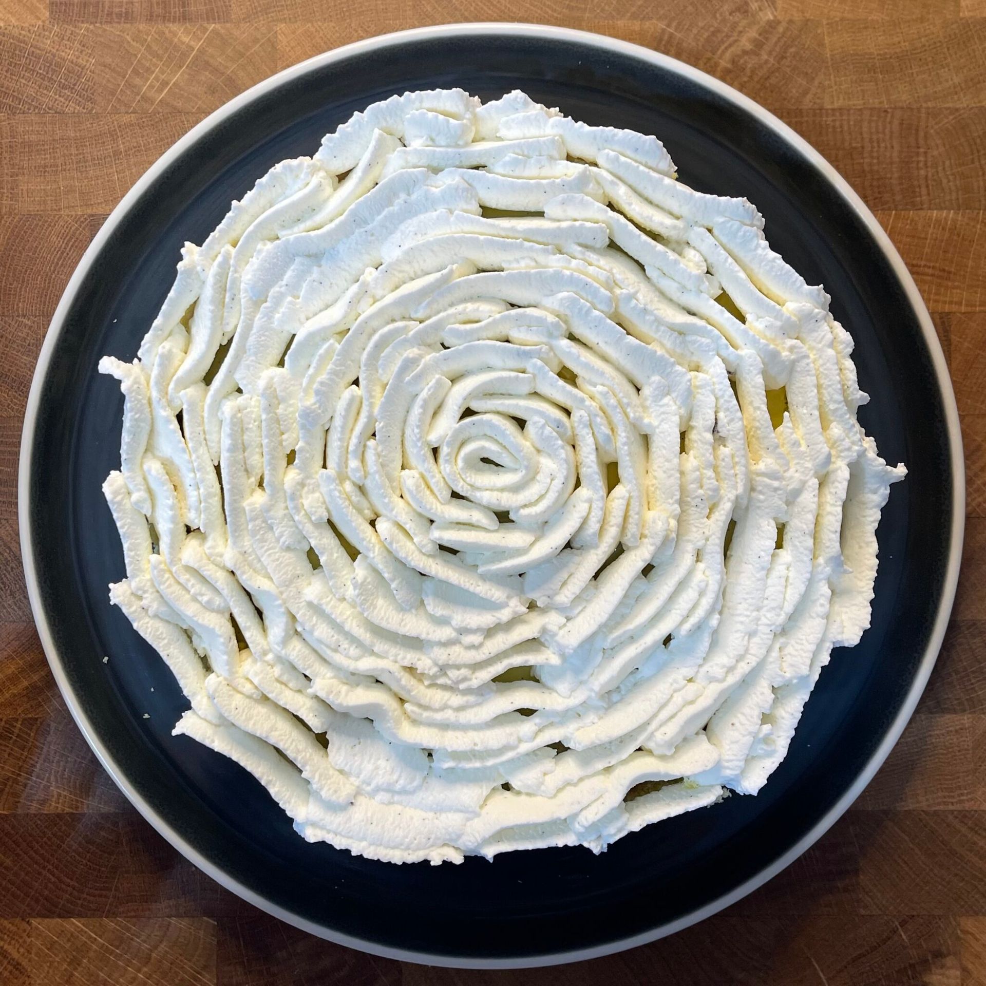 Un piatto nero con panna montata su un tavolo di legno
