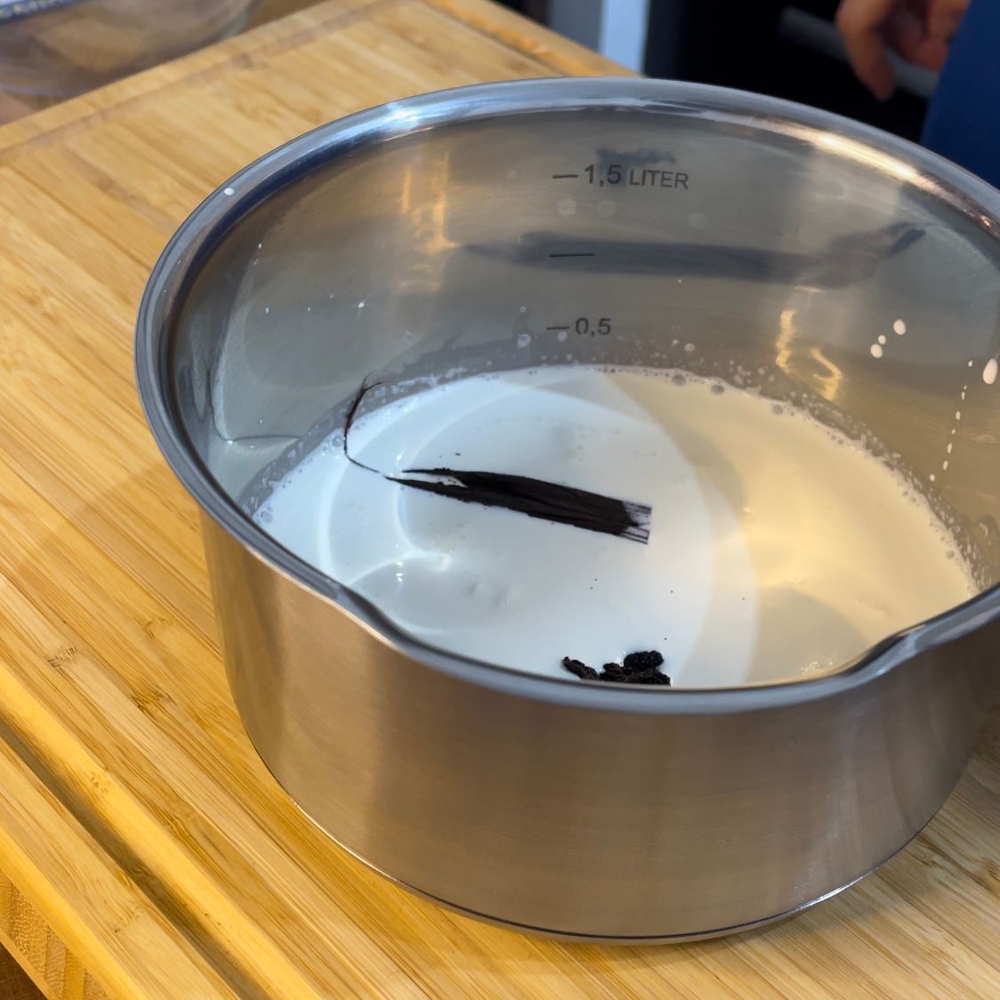 Una pentola di acciaio inossidabile piena di liquido bianco e un cucchiaio dentro