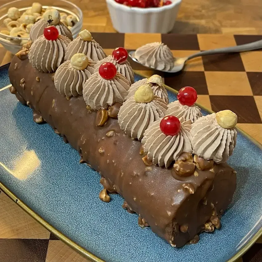 Un tronchetto di cioccolato è appoggiato su un tagliere nero.