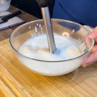 Una persona sta mescolando qualcosa in una ciotola con un frullatore