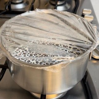 Una pentola ricoperta di pellicola trasparente è appoggiata sul fornello.