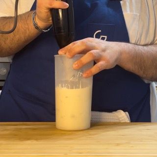 Un uomo con un grembiule sta versando del liquido in un misurino