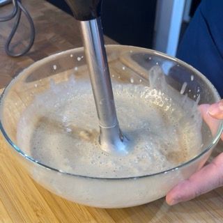 Una persona sta mescolando qualcosa in una ciotola con un frullatore