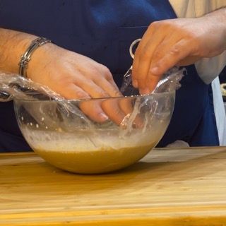 Una persona sta mescolando qualcosa in una ciotola con pellicola trasparente