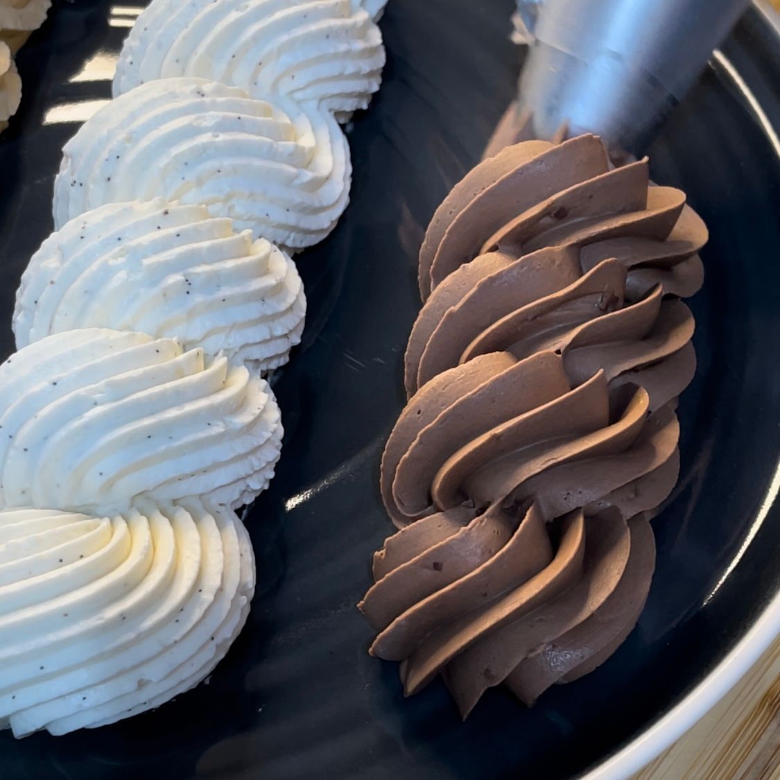 Un piatto nero con panna montata e glassa al cioccolato