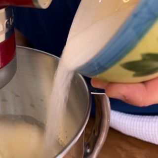 Aggiunta graduale dello zucchero agli albumi per la biscuit ricetta.