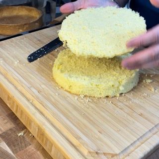 Una persona sta tagliando una torta su un tagliere di legno