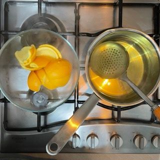 Due pentole sul fornello con dei limoni e un mestolo dentro