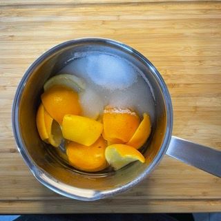 Una pentola piena di arance e limoni su un tavolo di legno