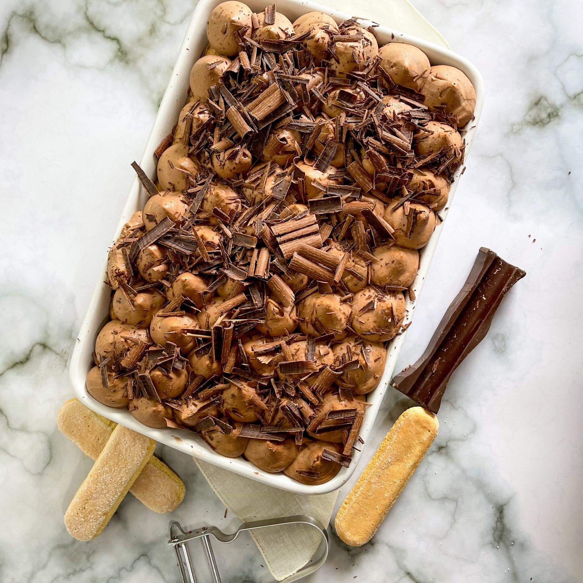 Una teglia bianca riempita con mousse al cioccolato e scaglie di cioccolato.