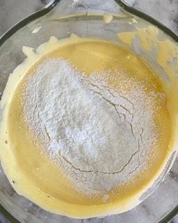 Una ciotola di vetro piena di un liquido giallo e zucchero a velo.