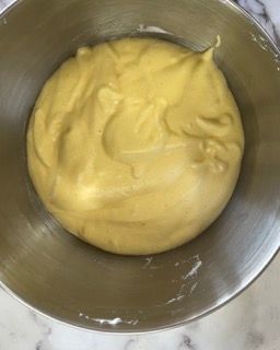 Una ciotola di salsa gialla è appoggiata su un tavolo.