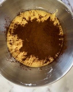 Una ciotola di metallo piena di un liquido marrone e di un liquido giallo.