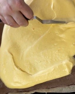 Una persona tiene una spatola sopra un mucchio di salsa gialla.