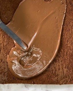 Si usa un cucchiaio per spalmare la glassa al cioccolato su una fetta di torta.