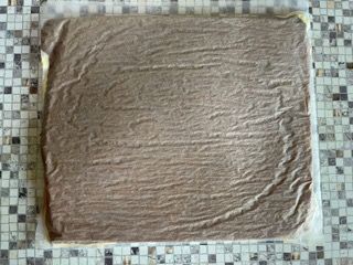 Un pezzo di torta al cioccolato è appoggiato su un bancone piastrellato.