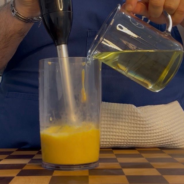 Minipimer a immersione che inizia a frullare mentre si versa la prima parte di olio.
