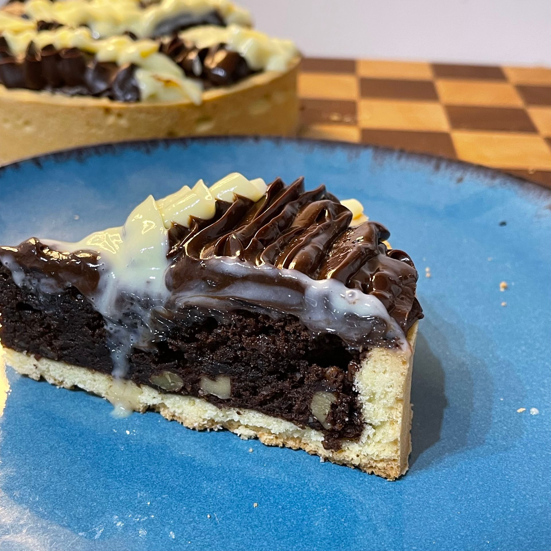 Fetta di crostata brownie che mostra il netto contrasto tra il guscio di pasta frolla croccante e il ripieno umido e fondente al cioccolato
