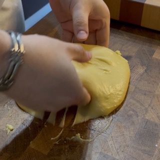 Mani che danno forza all'impasto sul piano di lavoro.