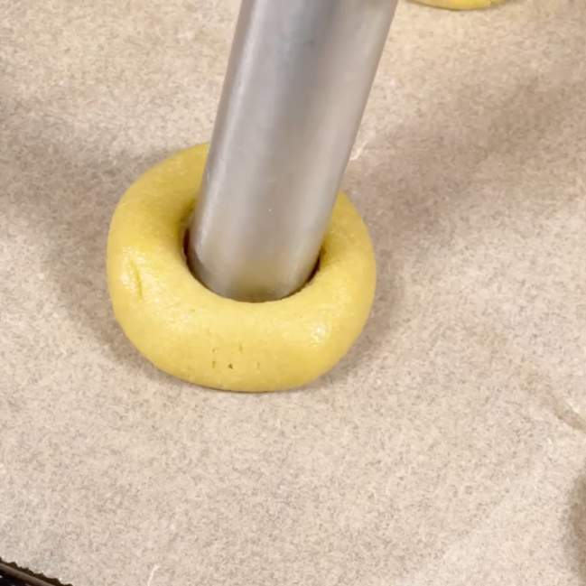Una ciambella gialla con un buco in mezzo è appoggiata su un tavolo.