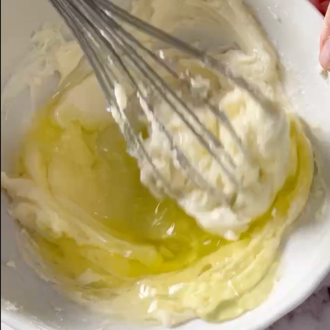 Si usa una frusta per mescolare un liquido giallo in una ciotola bianca.