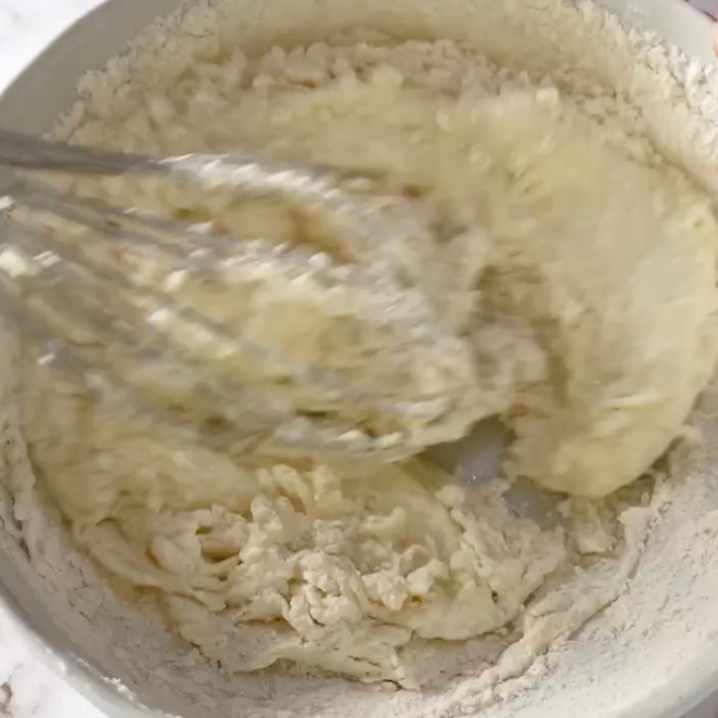 Primo piano di una ciotola di pastella con una frusta dentro.