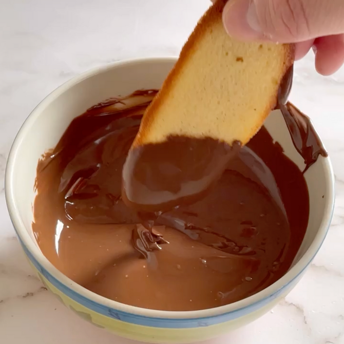 Una persona che immerge un pezzo di pane in una ciotola di salsa al cioccolato