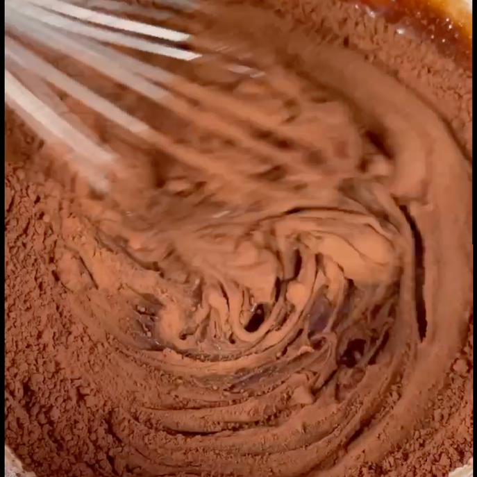 Un primo piano di una frusta in una ciotola di cioccolato in polvere
