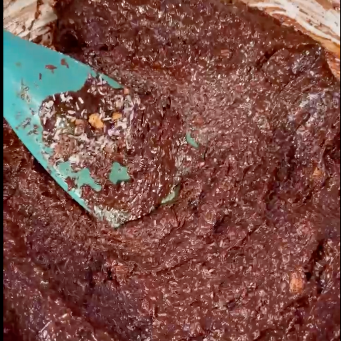 Un primo piano di un impasto per brownie con una spatola al suo interno.