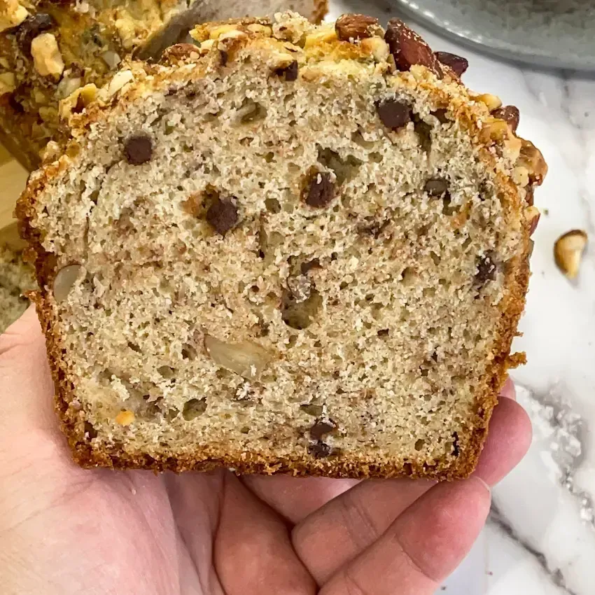 Fetta di banana bread morbido che mostra l'interno umido, l'alveolatura e le gocce di cioccolato fondente.