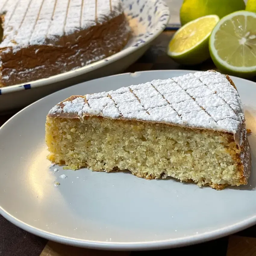 Fetta di torta caprese al limone morbida e umida con farina di mandorle e cioccolato bianco. Caprese