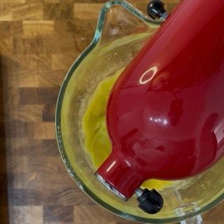 Versamento del succo di limone filtrato e mescolamento finale dell'impasto liquido senza glutine.