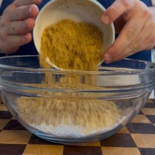 Unione della farina di mandorle e farina di nocciole in ciotola per la caprese con farina di mandorle.