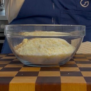 Tritatura finissima del cioccolato bianco su tagliere per la torta caprese al limone con cioccolato bianco.