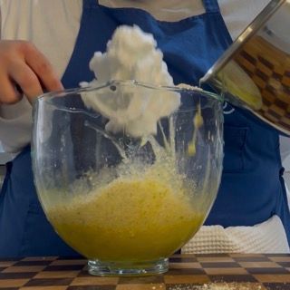 Inserimento del primo terzo di albumi montati a neve sopra l'impasto della torta caprese al limone.