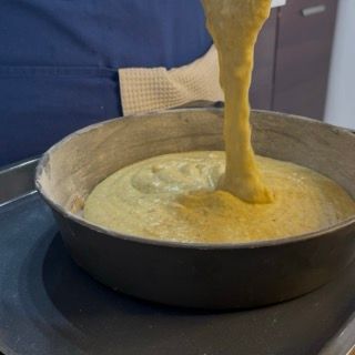 Versamento e livellamento dell'impasto con la spatola all'interno della teglia per caprese bianca.
