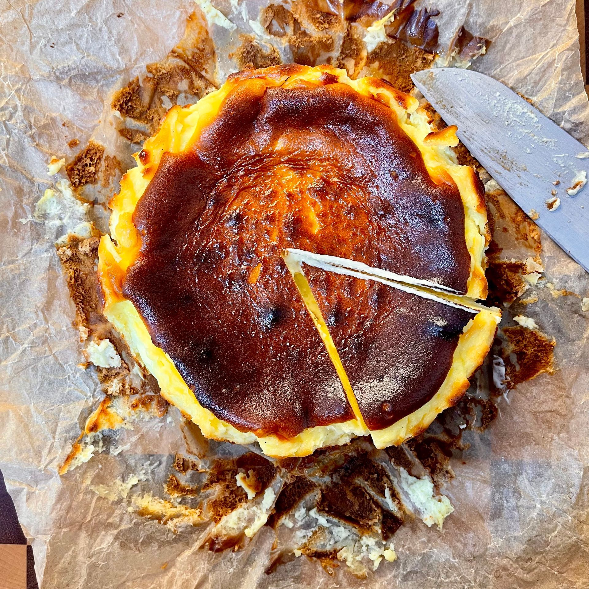 Cheesecake Basca intera con la sua tipica superficie scura e caramellizzata, effetto 'bruciato'.
