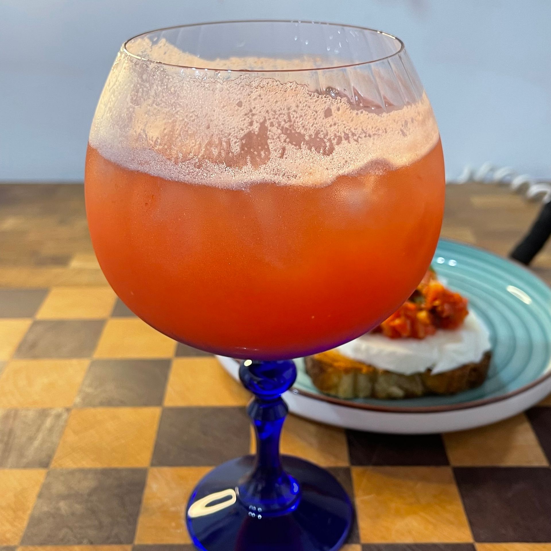 Dettaglio del cocktail analcolico pomodoro e melone con ghiaccio, basilico e tonica per un aperitivo estivo.