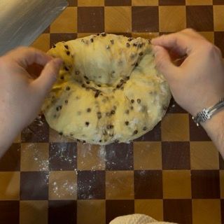 Mani che formano un panetto di Cramique, arrotolandolo stretto.