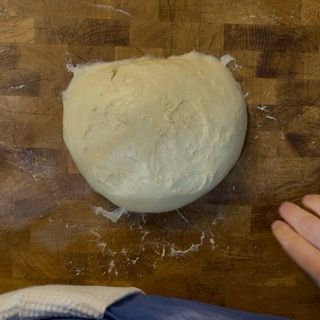 Mani che allargano delicatamente l'impasto sul piano di lavoro per il test del velo